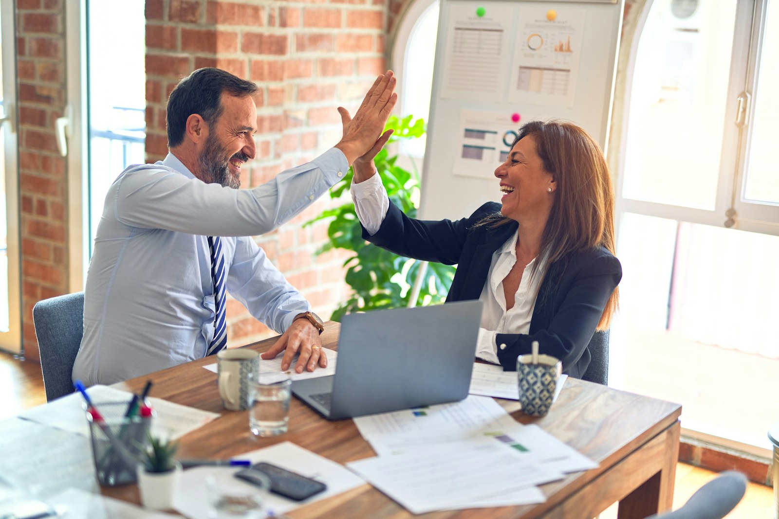 Executives shaking hands over a laptop